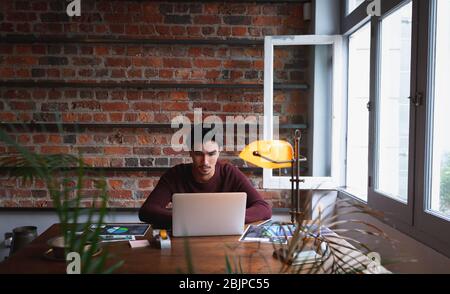 Giovane uomo che utilizza un computer portatile a casa Foto Stock