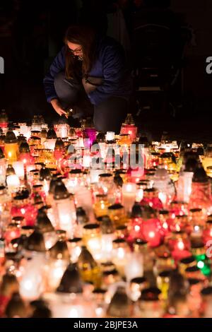 Una giovane donna accende una candela al monumento alle vittime polacche del comunismo al cimitero di Rakowicki a Cracovia, Polonia 2019. Foto Stock