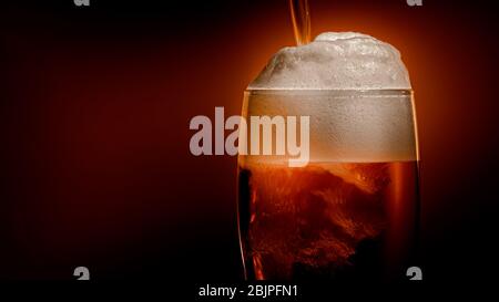 La birra lager si deposita nel bicchiere con un tappo bianco di schiuma Foto Stock
