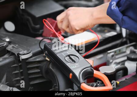 Giovane meccanico femminile che ripara l'auto in carrozzeria Foto Stock