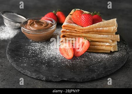 Piatto di ardesia con gustosi pancake sottili di grano saraceno sul tavolo Foto Stock