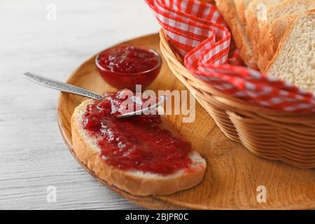 Pane con marmellata di fragole su piastra di legno Foto Stock