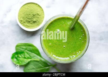 Vista dall'alto e ravvicinata di un frullato di spinaci fatti in casa con una paglia da bere in acciaio inossidabile Foto Stock