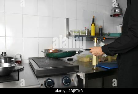 Chef flambing verdure in cucina ristorante Foto Stock