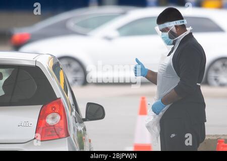 Un tester che indossa i gesti dei dispositivi di protezione individuale (PPE) per un conducente durante un viaggio attraverso il sito di test dei coronavirus presso IKEA a Wembley, a nord di Londra. Foto Stock