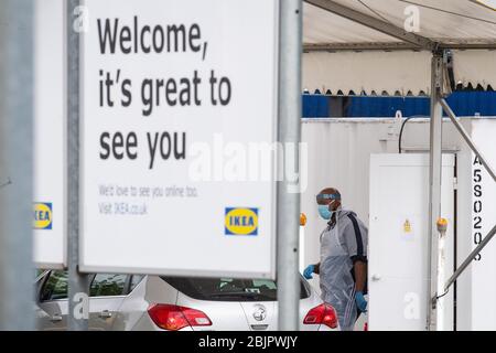 Un tester che indossa i dispositivi di protezione individuale (PPE) cammina verso un'auto a un viaggio attraverso il sito di test dei coronavirus presso IKEA a Wembley, a nord di Londra. Foto Stock
