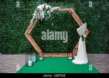 Arco di nozze per la cerimonia del legno, decorato con rose rosa dewy e glicine su uno sfondo di foglie verdi. Composizione floreale per matrimoni. COP Foto Stock