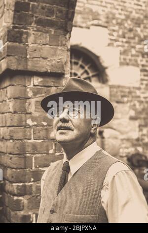 Vintage seppia 1940 uomo in elegante gilet e cappello, isolati all'aperto guardando fino al cielo, 1940 guerra seconda estate evento UK. Ci incontreremo di nuovo. Foto Stock