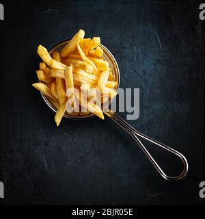 Patatine fritte in un elegante cesto di metallo su sfondo nero. Vista dall'alto. Foto Stock