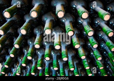 Bottiglie di vino polverose impilate in una cantina Foto Stock