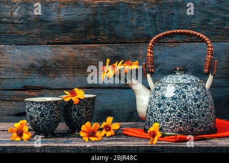 Ancora vita con i fiori di Chernobrivtsi in teiera vintage e tazze su sfondo rustico vecchio. Foto Stock