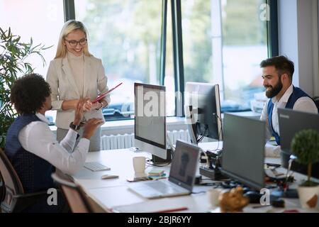 soddisfatto giovane capo bionda femmina che ascolta le idee del dipendente, sorridente. concetto di business casual di successo Foto Stock