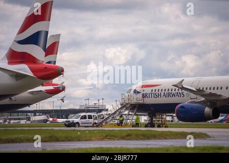 Glasgow, Regno Unito. 30 Aprile 2020. Nella foto: Le nuvole tempesta si riuniscono mentre gli equipaggi di terra della British Airways assistono alla raccolta di 14 aeromobili Airbus A319/A320 e A321 collegati a terra che sono stati parcheggiati sulla seconda pista dell'aeroporto di Glasgow dall'inizio del blocco Coronavirus (COVID-19). Da allora, l'industria globale delle compagnie aeree è andata in tracollo con alcune compagnie aeree che vanno in fallimento e altre come BA che chiedono assistenza finanziaria al governo. Ad oggi BA ha annunciato che è axing quasi 12,000 personale. Credit: Colin Fisher/Alamy Live News Foto Stock