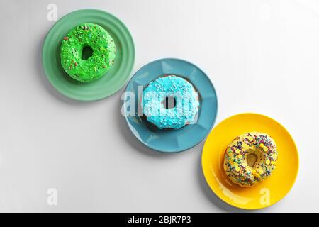 Piatti con ciambelle diverse su sfondo bianco Foto Stock