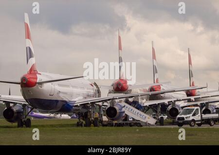 Glasgow, Regno Unito. 30 Aprile 2020. Nella foto: Le nuvole tempesta si riuniscono mentre gli equipaggi di terra della British Airways assistono alla raccolta di 14 aeromobili Airbus A319/A320 e A321 collegati a terra che sono stati parcheggiati sulla seconda pista dell'aeroporto di Glasgow dall'inizio del blocco Coronavirus (COVID-19). Da allora, l'industria globale delle compagnie aeree è andata in tracollo con alcune compagnie aeree che vanno in fallimento e altre come BA che chiedono assistenza finanziaria al governo. Ad oggi BA ha annunciato che è axing quasi 12,000 personale. Credit: Colin Fisher/Alamy Live News Foto Stock