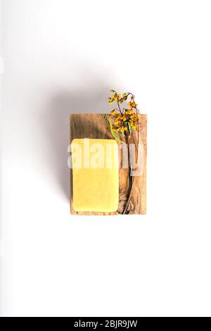 Sapone su barra di legno con erbe secche su sfondo di carta bianca. Concetto di salute e bellezza. Foto Stock