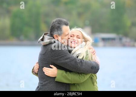 Felice coppia matura abbracciando sul lungofiume Foto Stock