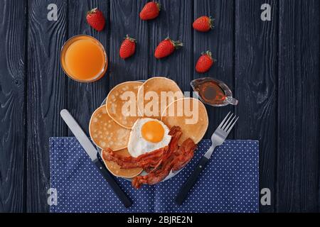 Piatto con frittelle, uova fritte e pancetta sul tavolo, vista dall'alto Foto Stock