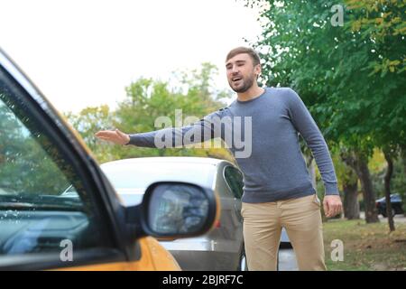 Giovane uomo prendere taxi sulla strada della città Foto Stock