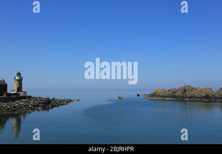 Una piccola barca lascia il porto di Portpatrick in una tranquilla giornata di sole. Foto Stock