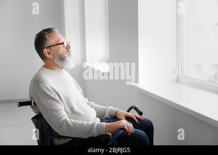 Uomo anziano in sedia a rotelle in camera vuota Foto Stock