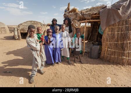 Agadez, Niger : tribù africana di famiglia Djerba in abiti tradizionali colorati di fronte alla loro casa nel deserto del Sahara sul boarder o Foto Stock