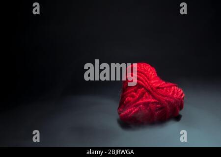 Cuore rosso fatto di fili di fumo su uno sfondo scuro sotto la luce di un riflettore Foto Stock