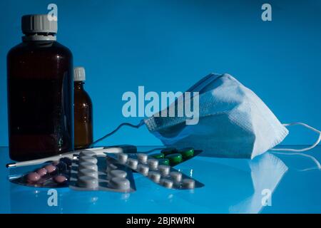 vasetti medici, termometro, siringa, maschera di garza e pillole medicine, medicina su sfondo blu vetro primo piano. spazio per le copie Foto Stock
