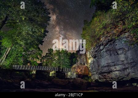 Il cuore della Via Lattea può essere visto appena sopra la linea degli alberi e il mulino di grrist in una notte di tarda estate nel Babcock state Park, Virginia Occidentale. Foto Stock