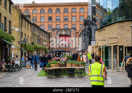 LONDRA - 30 SETTEMBRE 2019: Una sala da pranzo all'aperto nel Camden Market con vecchi magazzini sullo sfondo Foto Stock