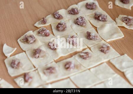 donna mettere carne macinata ogni parte di impasto quadrato. ingredienti di manti sono carne macinata, prezzemolo e cipolla. Manti è lo stile turco del gnocco Foto Stock