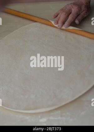 Mani cottura pasta con laminello su tavola di legno per piatti turchi manti. Manti è un tipo di gnocchi popolare nella maggior parte delle cucine turche Foto Stock