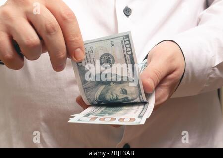 L'uomo caucasico conta soldi cento fatture del dollaro in una camicia bianca nell'ufficio Foto Stock