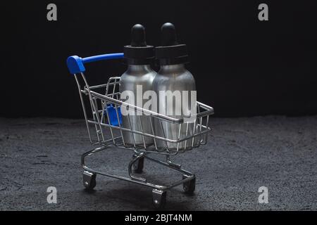 vasetti in alluminio con pipette per olio liquido in un carrello magozino su cemento nero Foto Stock