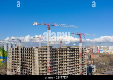 Costruzione gru un edificio a più piani con appartamenti su uno sfondo di cielo blu con nuvole, vista aerea droni Foto Stock