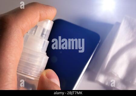 disinfettante spray per mani sul telefono cellulare per la pulizia e la protezione dai virus. messa a fuoco selettiva Foto Stock