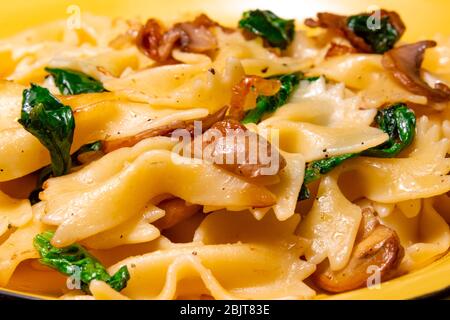 pasta farfalla con funghi fritti, spinaci verdi Foto Stock