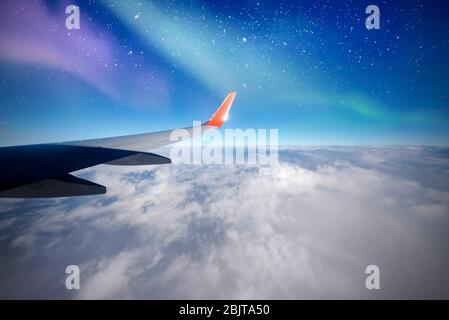 Aereo sopra nord, aurora o nord dalla finestra dell'aereo, aurora boreale, cielo notturno con nuvole e stelle Foto Stock