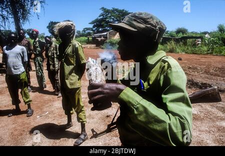 Sudan Peoples Liberation Esercito soldato fumare in un villaggio vicino a Yei, Repubblica del Sud Sudan, Africa Foto Stock