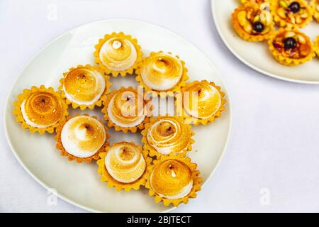 Appetitosi biscotti con meringa e crema su un tavolo da banchetto bianco. Pancake in un ristorante a buffet. Candy bar per gli ospiti di un matrimonio. Tart Foto Stock