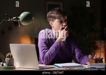Adolescente che fa i compiti a tavola in serata Foto Stock