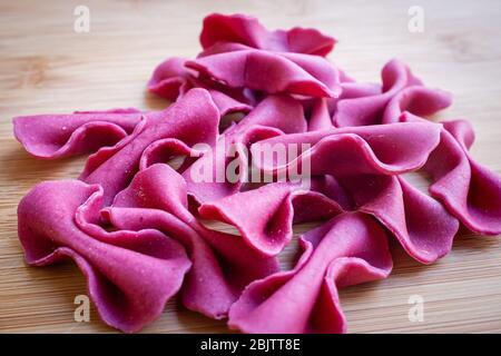 Primo piano della pasta fresca di farfalle di colore viola chiamata farfalle. Autentica cucina italiana Foto Stock