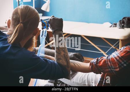 Artista professionale rendendo tatuaggio in salone Foto Stock