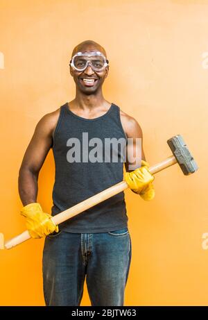 Un ritratto di un uomo afro-americano con un martello a slitta che indossa la protezione degli occhi. Foto Stock