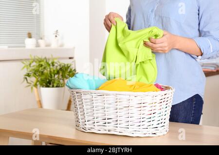 Donna che ordina lavanderia sul tavolo, al chiuso Foto Stock