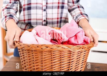 Donna che tiene il cesto con la biancheria sporca, al chiuso Foto Stock