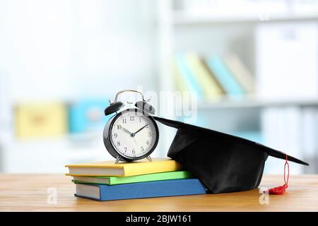 Sveglia, tappo graduato e libri di testo sul tavolo. Obiettivi dello studio Foto Stock