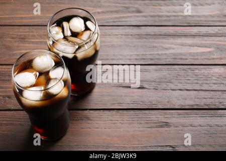 Due bicchieri di cola rinfrescante con ghiaccio su tavolo di legno Foto Stock