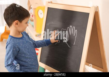 Ragazzo che mette la sua palma sul disegno all'ufficio dello psicologo del bambino. Concetto di autismo Foto Stock