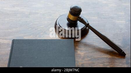 Tema della legge. Giudice gavel e un libro nero vuoto legale su sfondo di scrivania in legno, spazio copia. Asta, tavolo da tribunale Foto Stock